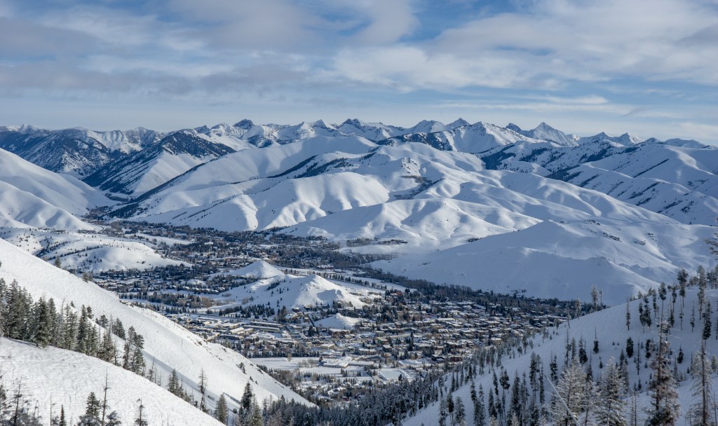 Aerial view of Ketchum, Idaho, nestled in a snow-covered valley surrounded by mountains.