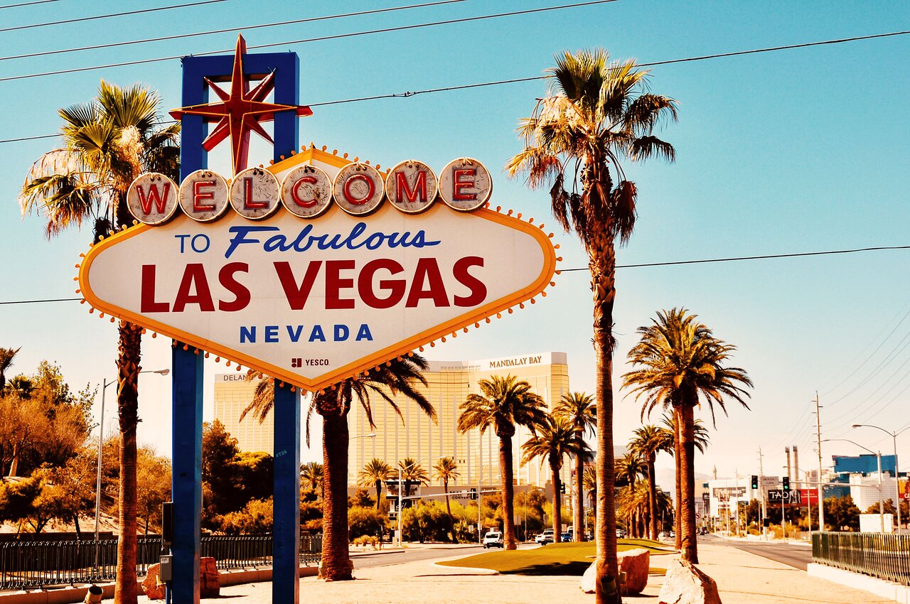 The iconic "Welcome to Fabulous Las Vegas" sign lit up at night with bright lights against a dark sky.