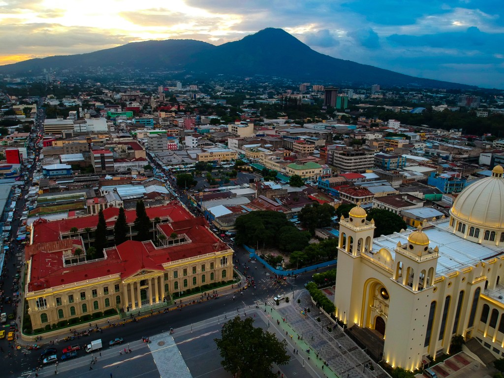 Aerial view of San Salvador showing the Metropolitan Cathedral, National Palace, and the San Salvador Volcano.